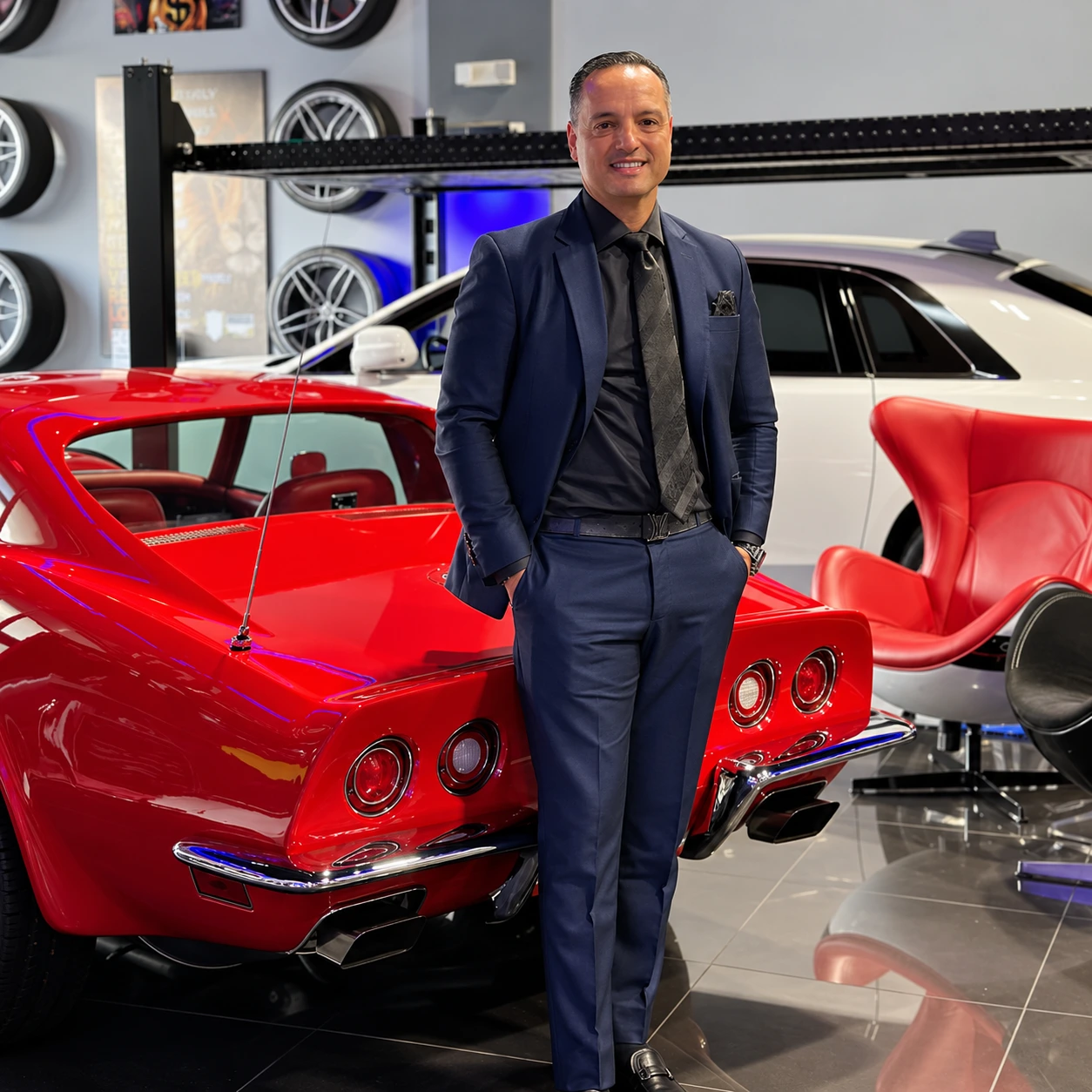 Dr. Raúl González junto a un automóvil clásico rojo